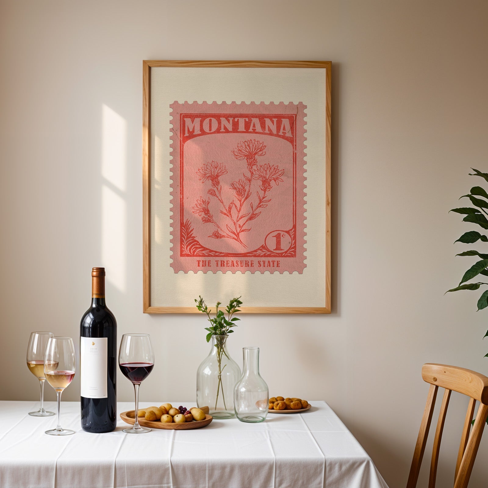 Montana stamp print framed on the wall above a dining table set with wine, glasses and olives