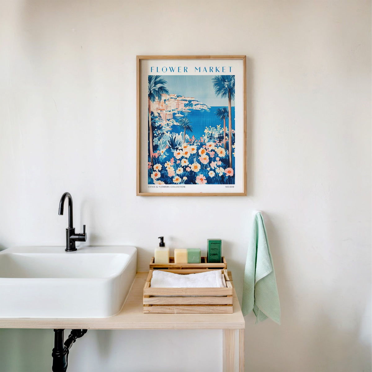 Monte Carlo flower market print in an oak frame above a white bathroom sink with folded towels