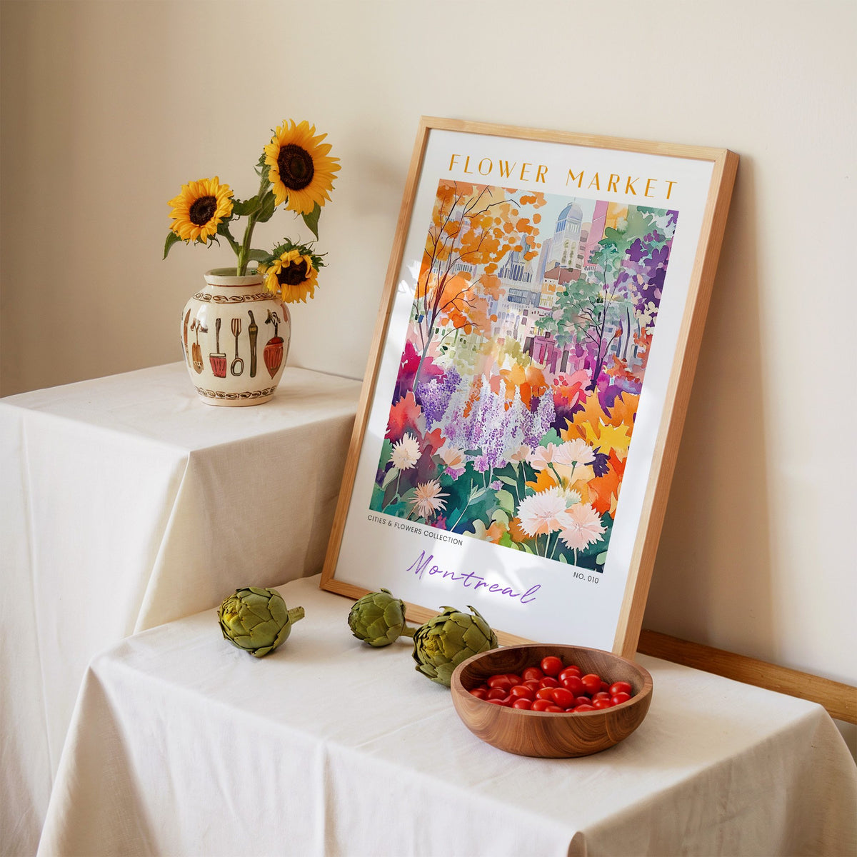 Montreal flower market print in an oak frame leaning on a linen-draped table beside a vase of sunflowers