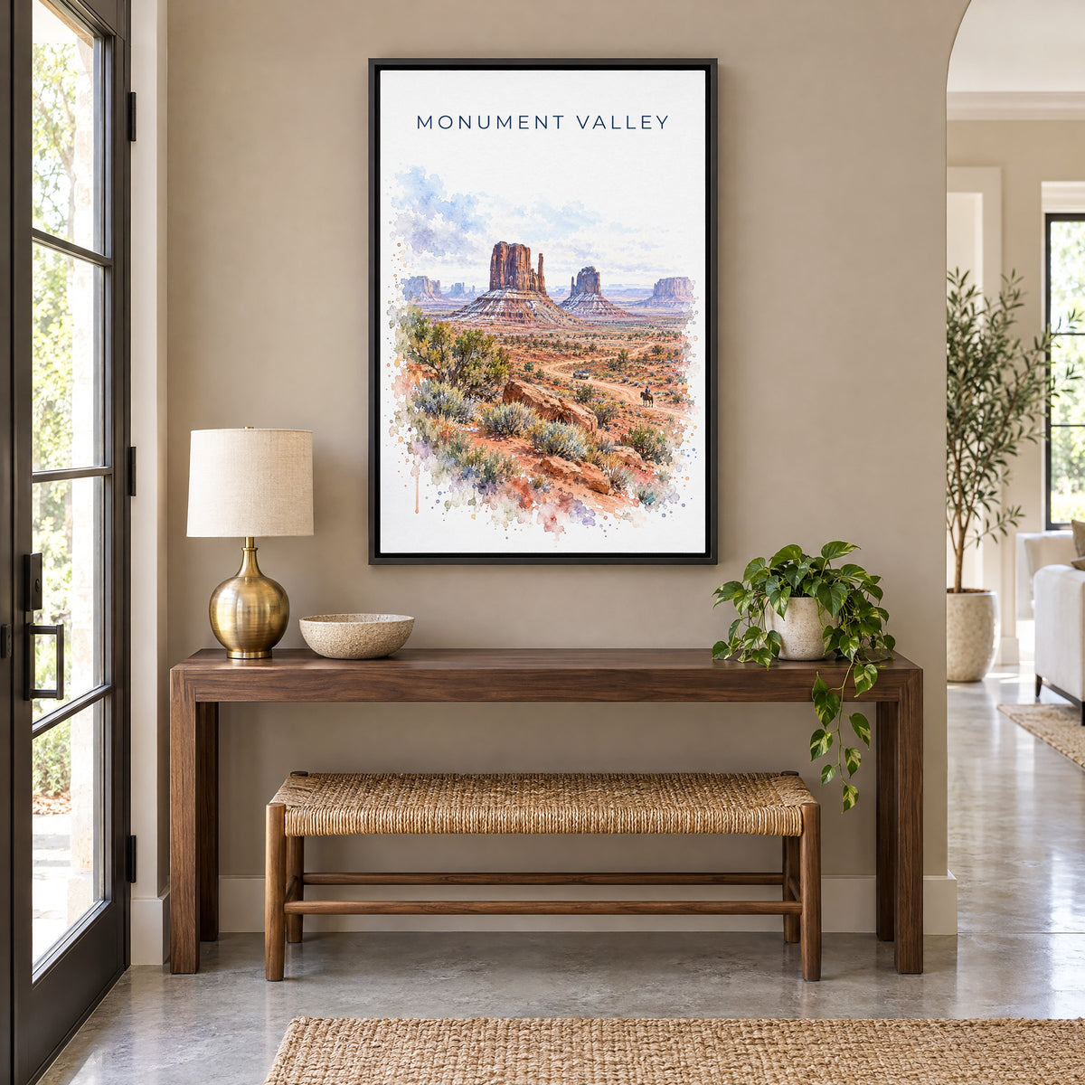 Monument Valley watercolor print as a black floater canvas above a walnut console and woven bench in an entryway