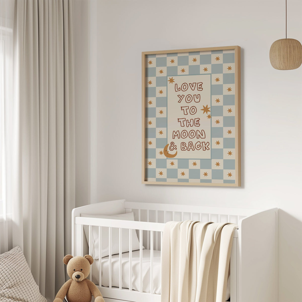 Love you to the moon nursery print in an oak frame above a white crib with a teddy bear