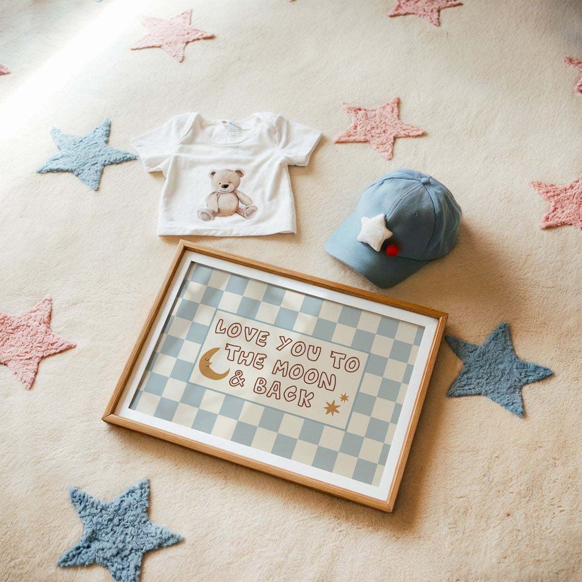 Landscape love you to the moon nursery print in a matted oak frame on a star rug with a baby tee