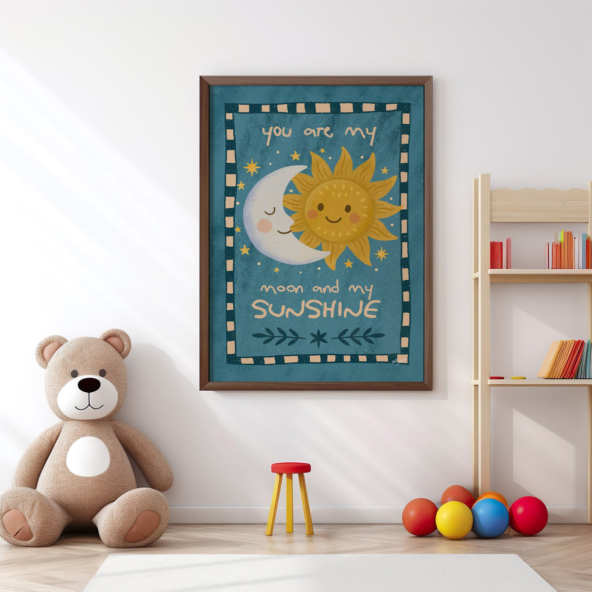 Sleepy moon and smiling sun nursery print in a walnut frame above a big teddy bear by a bookshelf