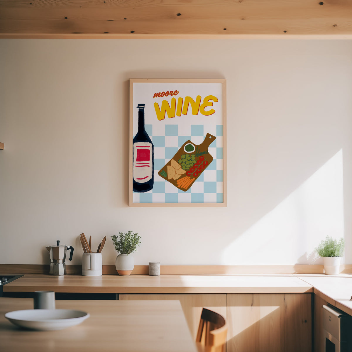 Wine and cheese board print in an oak frame above a wood counter with a moka pot and herbs