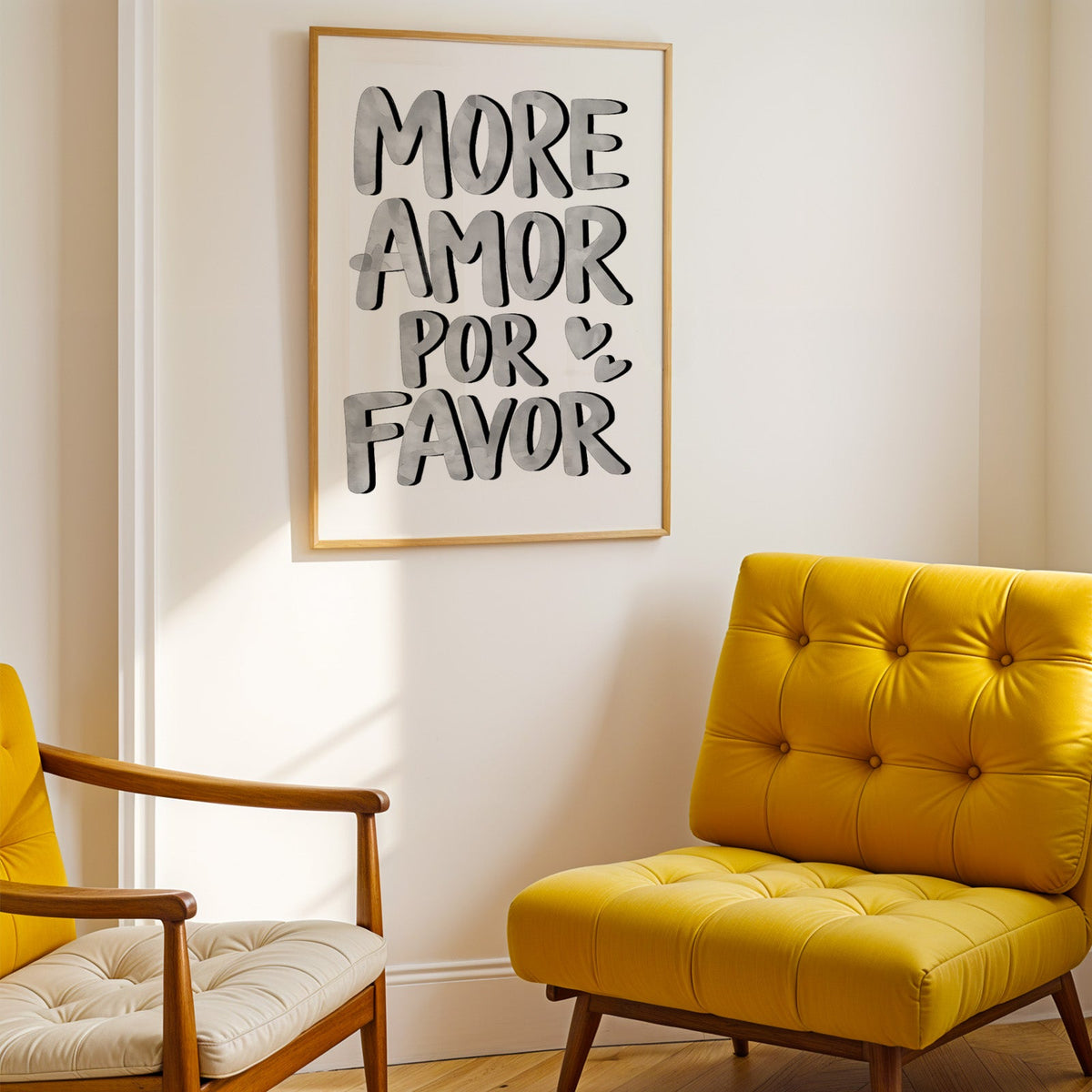 More amor por favor grey lettering print shown in a gold frame above a mustard yellow tufted armchair