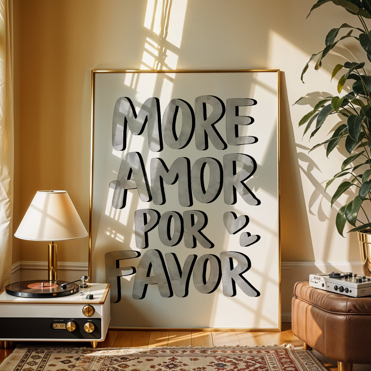 More amor por favor grey lettering print shown in a gold frame beside a record player and table lamp