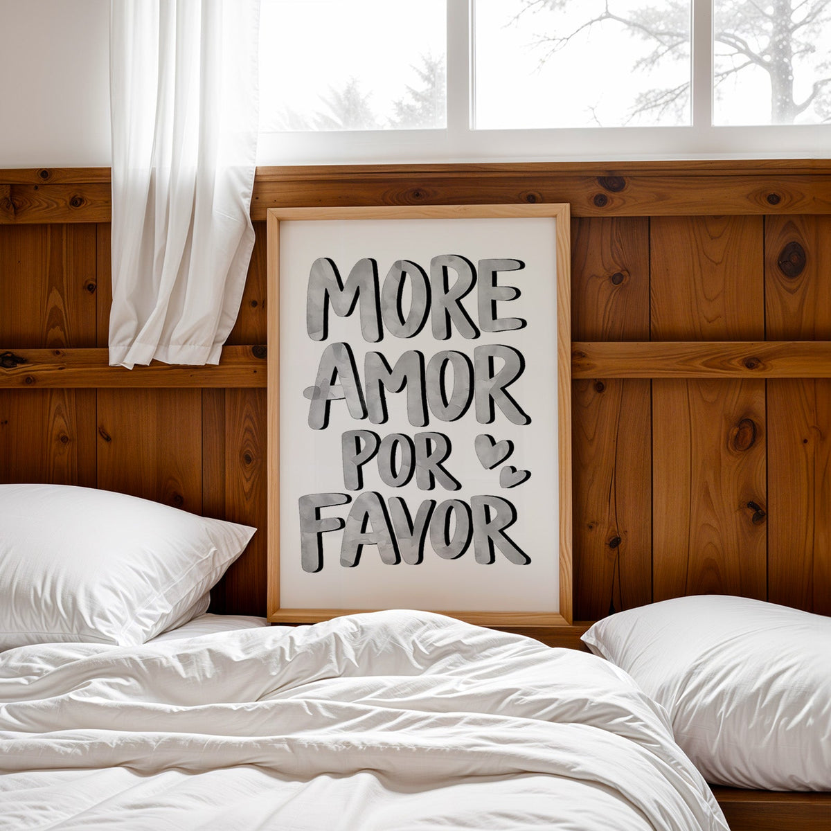 More amor por favor grey lettering print in a pine frame leaning on a wood headboard over white bedding