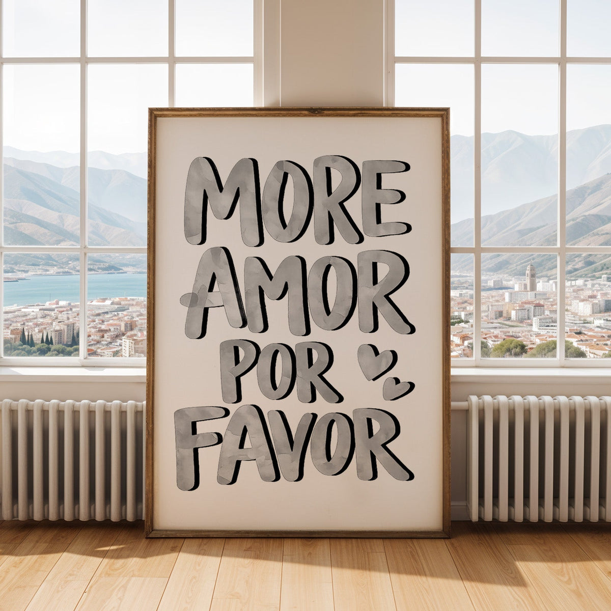 More amor por favor grey lettering print shown in an antique gold frame by tall windows with a sea view