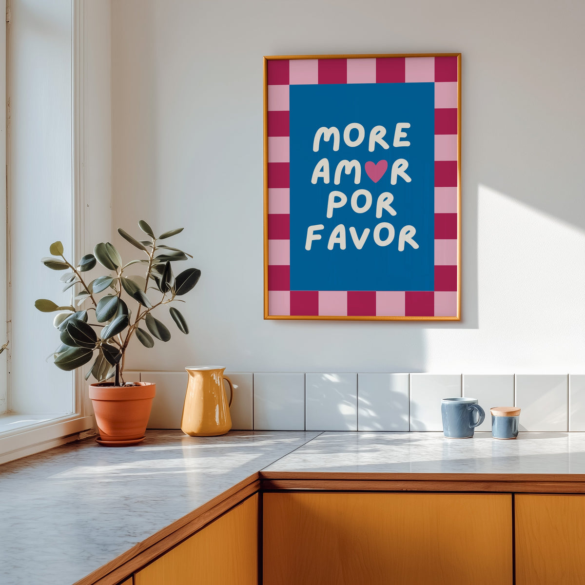 More Amor Por Favor print shown in a gold frame above a marble counter with a yellow ceramic jug