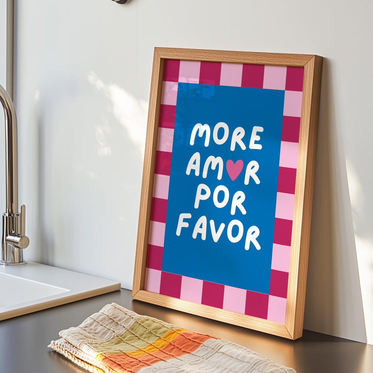 More Amor Por Favor print in an oak frame by the kitchen sink beside a striped tea towel