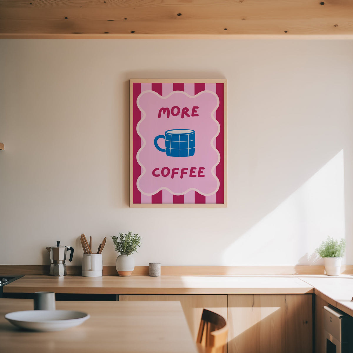 More Coffee mug print in an oak frame above a wood counter with a moka pot and herbs