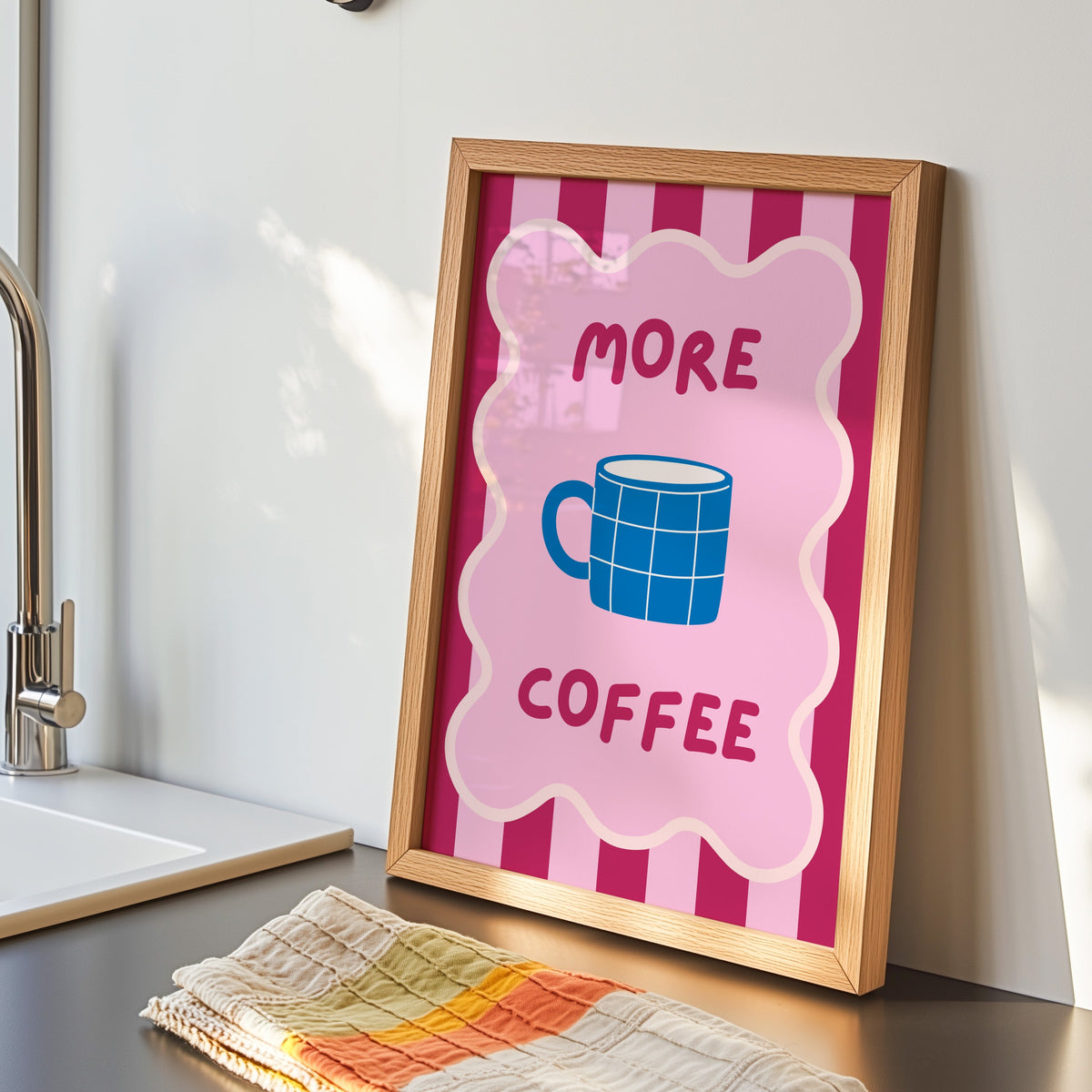 More Coffee mug print in an oak frame by the kitchen sink beside a striped tea towel