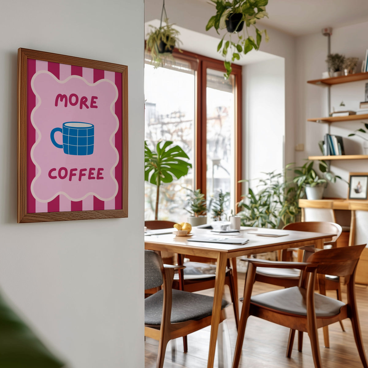 More Coffee mug print in a walnut frame beside a mid-century dining table