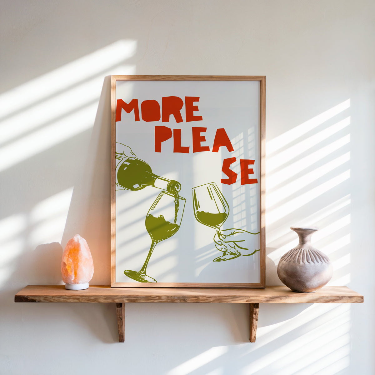 More Please wine pour print in an oak frame on a live-edge shelf beside a salt lamp