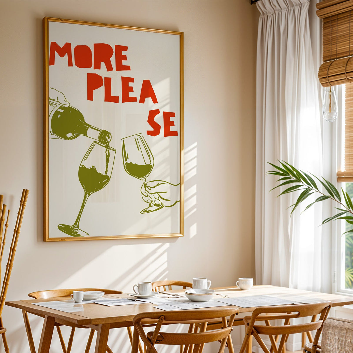 More Please wine pour print shown in a gold frame above a breakfast table by a curtained window