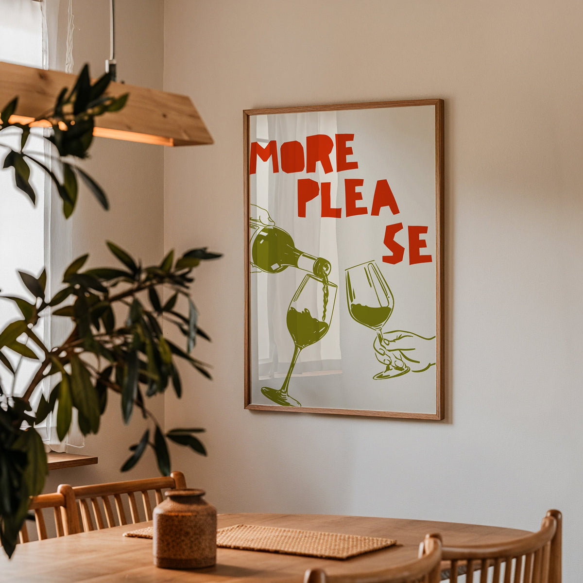 More Please wine pour print in a walnut frame above a dining table with olive branches