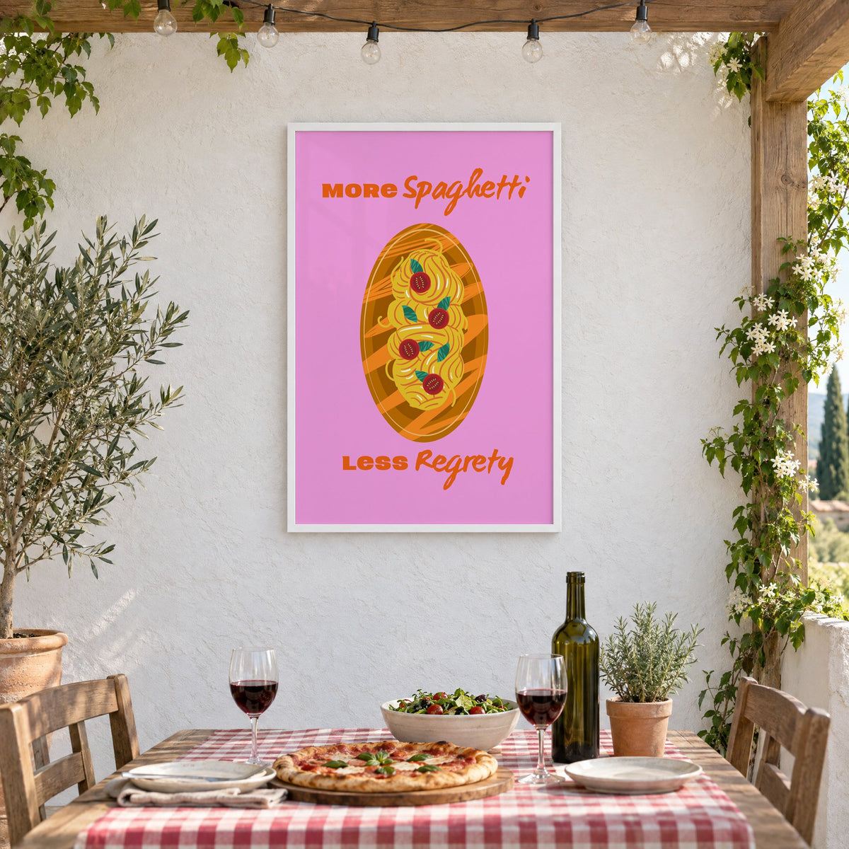 MORE Spaghetti LESS Regrety pasta plate print in a white frame on a stucco wall above a checked-cloth table with pizza and red wine
