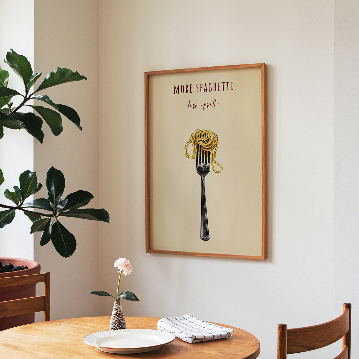 More Spaghetti Less Upsetti print in a walnut frame above a round table beside a fiddle-leaf fig