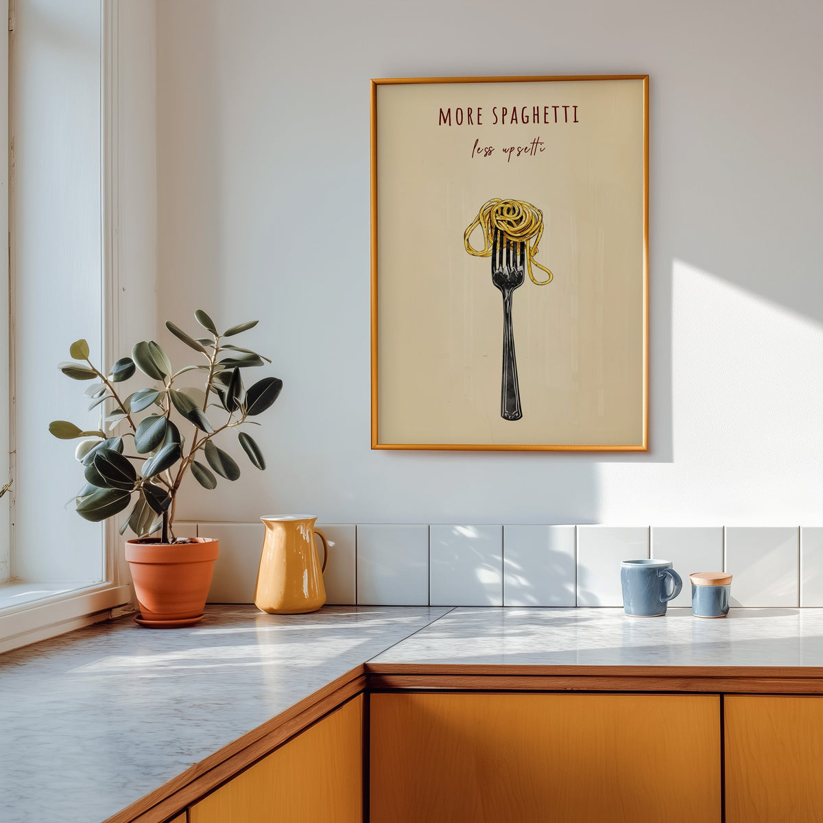 More Spaghetti Less Upsetti print shown in a gold frame above a marble counter in a tan kitchen