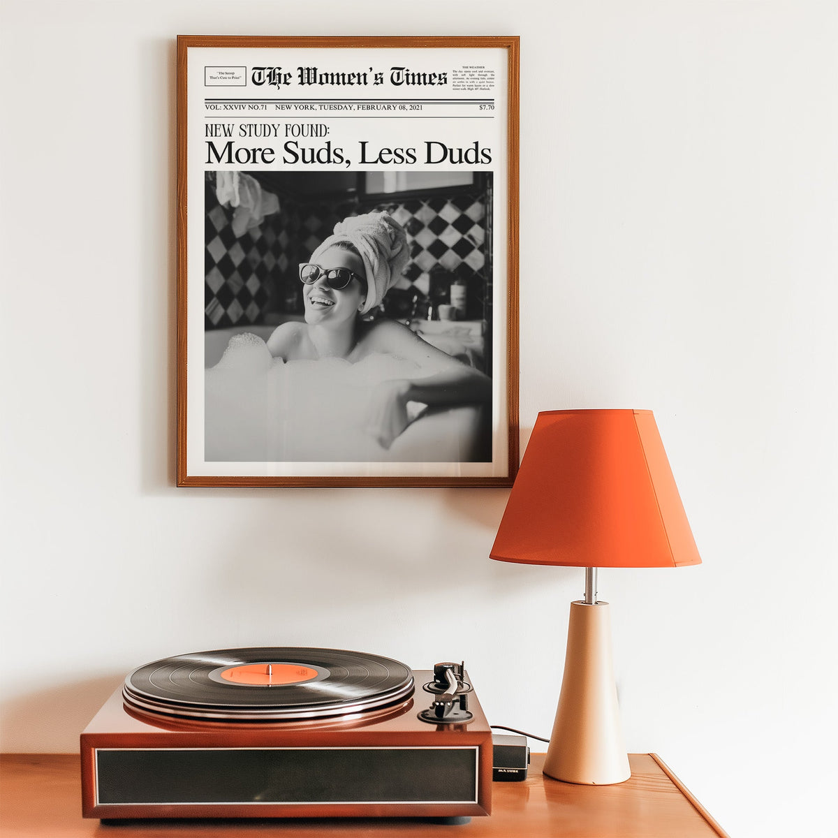 Woman in bubble bath mock newspaper print in a walnut frame above a record player and orange lamp