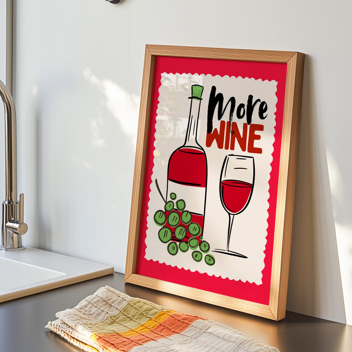 More Wine print in an oak frame by the kitchen sink beside a striped tea towel