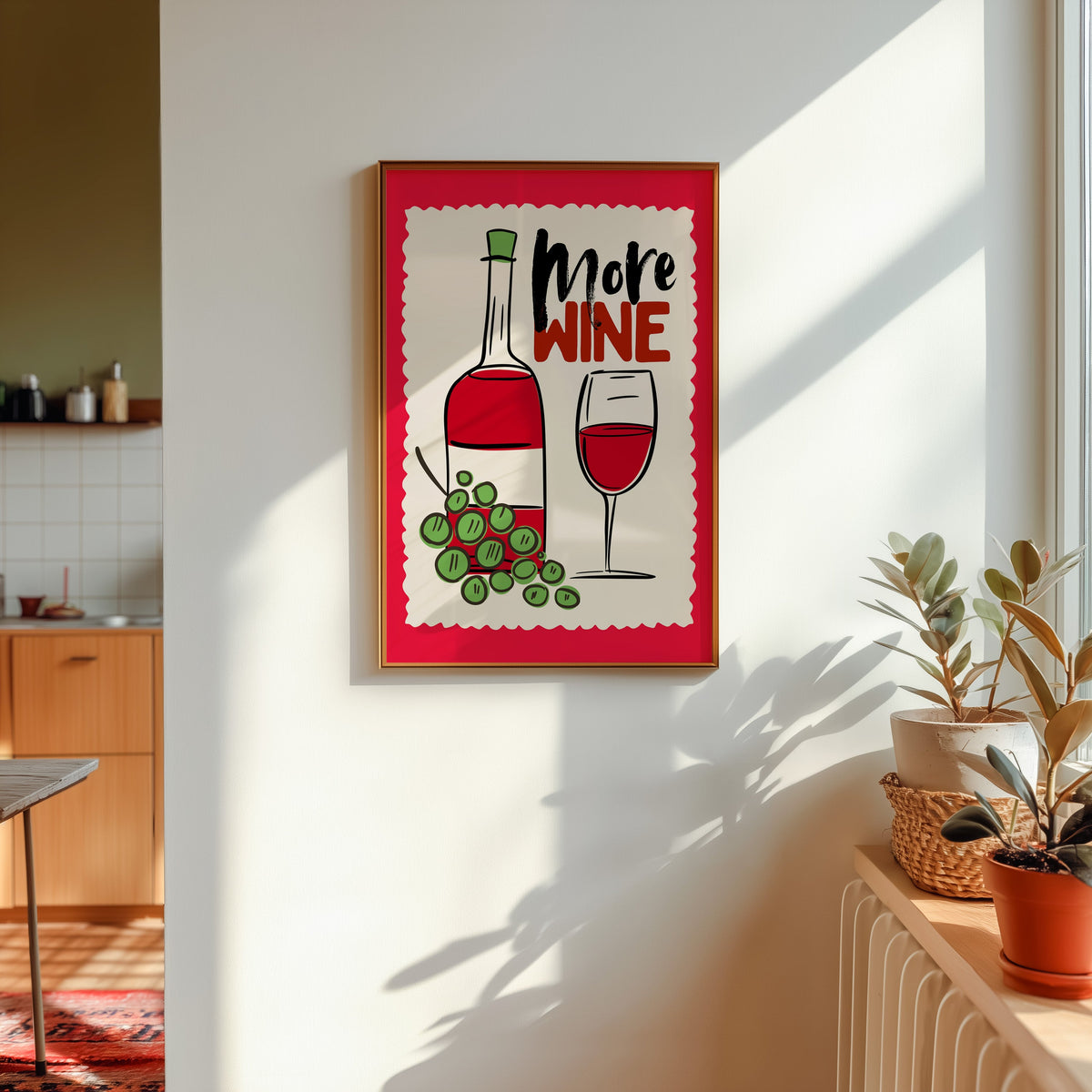 More Wine print in a gold frame in sunlight with plants and a kitchen beyond