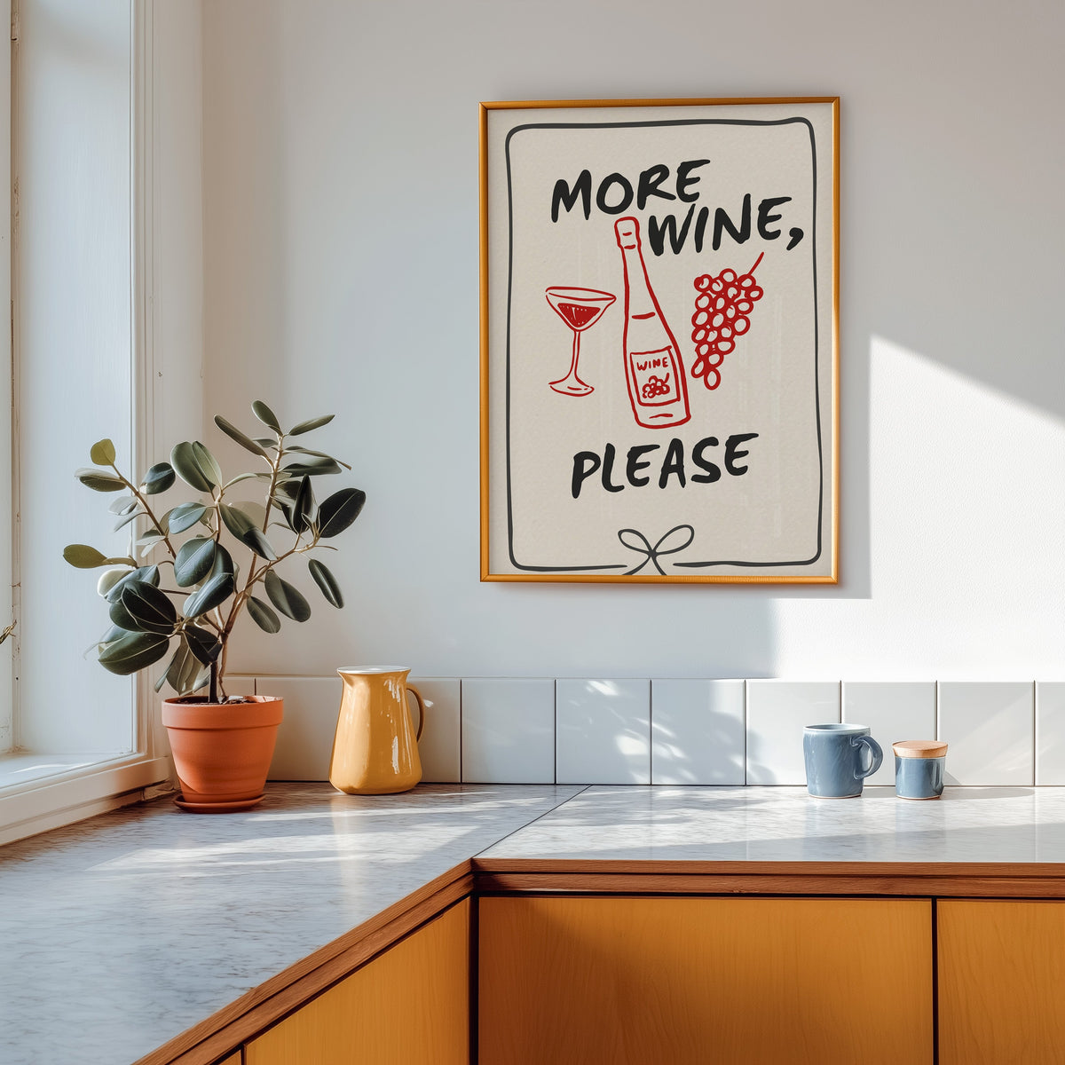 More Wine Please print shown in a gold frame above a marble counter with a yellow ceramic jug