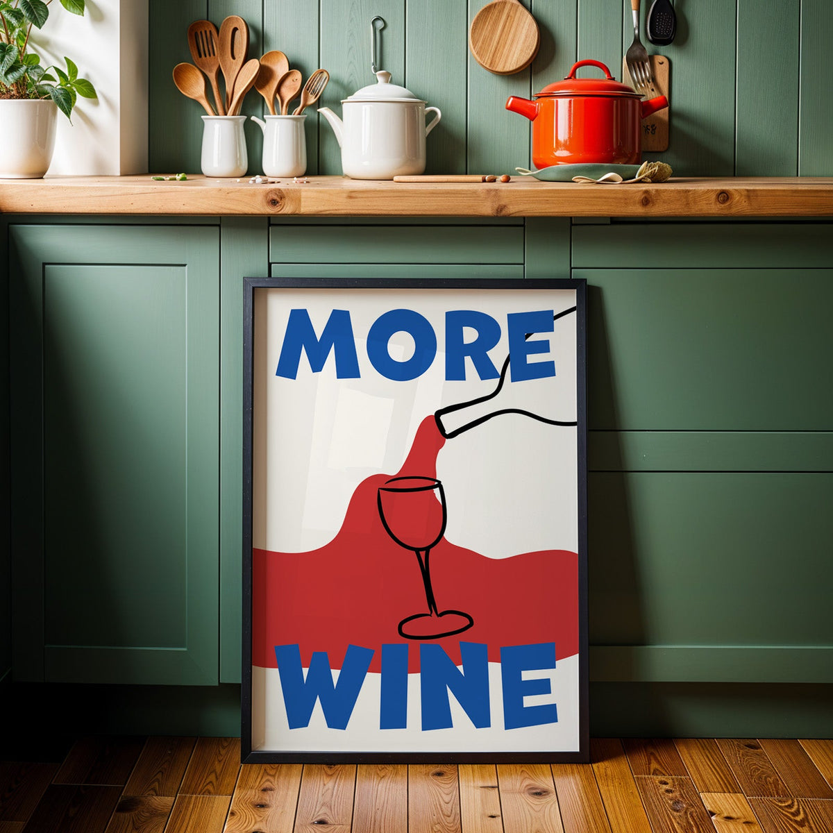 More wine red pour print in a black frame against sage green kitchen cabinets