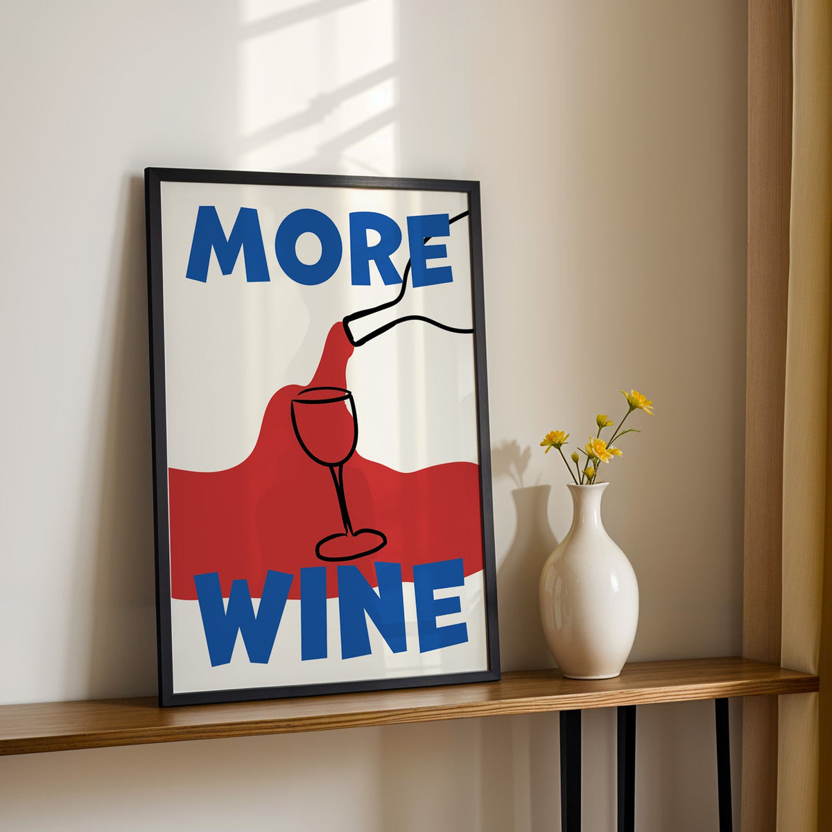 More wine red pour print in a black frame on a console table with yellow daisies