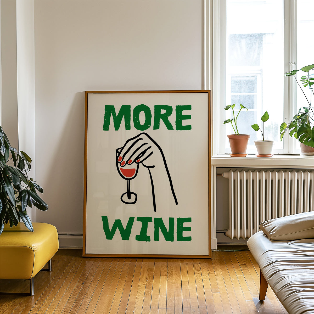 More Wine upside down glass print in an oak frame leaning on a wooden floor beside a yellow leather bench