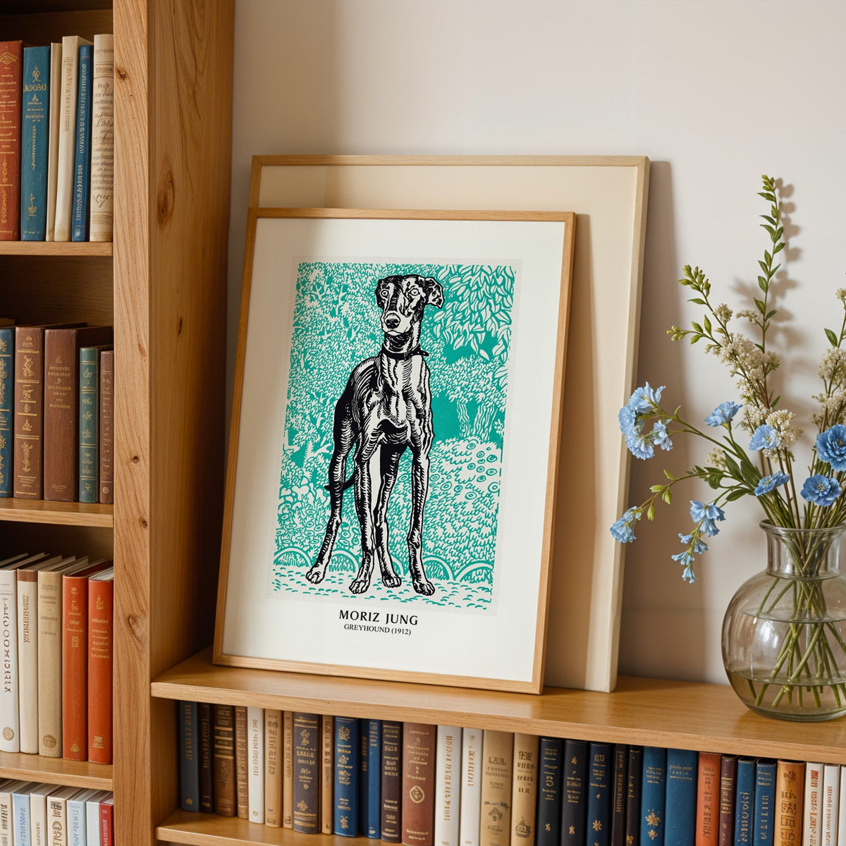 Dog print in an oak frame leaning on a bookshelf beside blue flowers