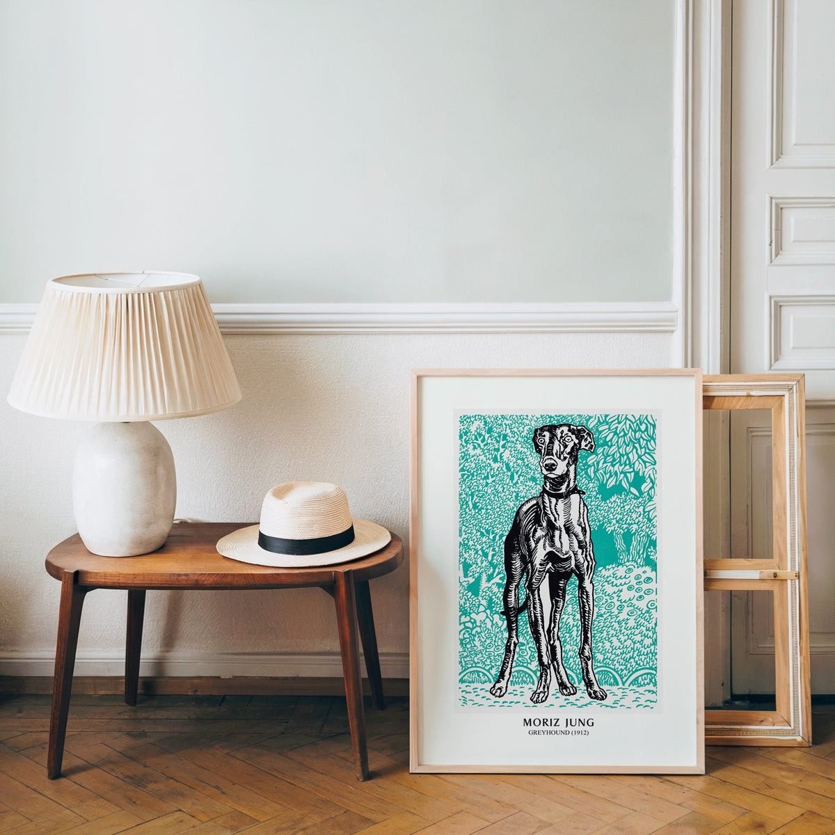 Vienna graphic dog poster in a light wood frame leaning by a bench and hat