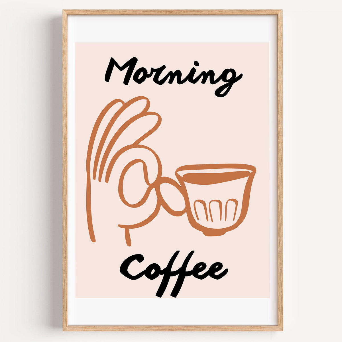 Morning Coffee terracotta hand cup print in a light oak frame on a plain white wall