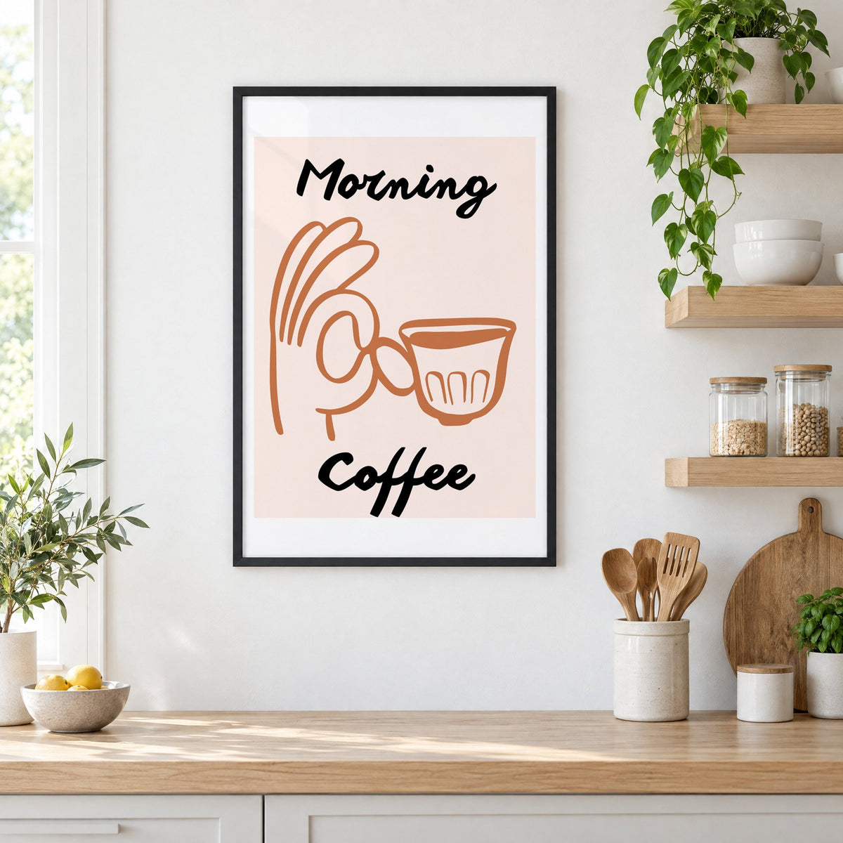 Morning Coffee terracotta hand cup print in a black frame in a white kitchen beside open wood shelves and glass jars