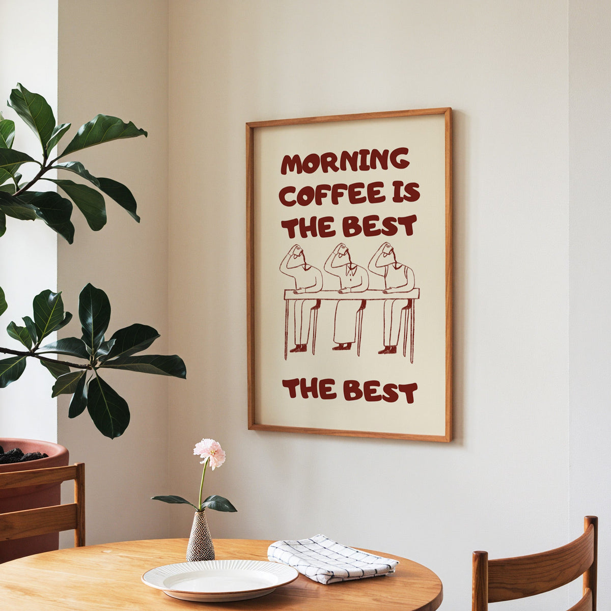 Morning Coffee Is The Best print in a walnut frame above a round table beside a fiddle-leaf fig
