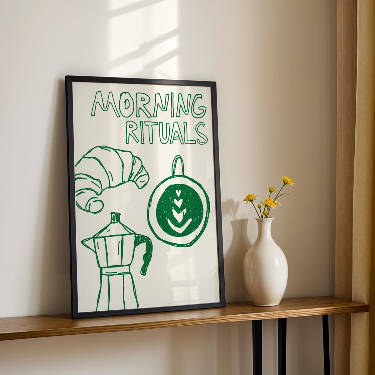 Morning rituals coffee line print in a black frame on a console table with daisies