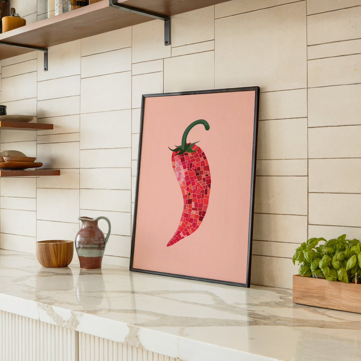 Mosaic chilli print in a black frame leaning on a marble counter in a tiled kitchen