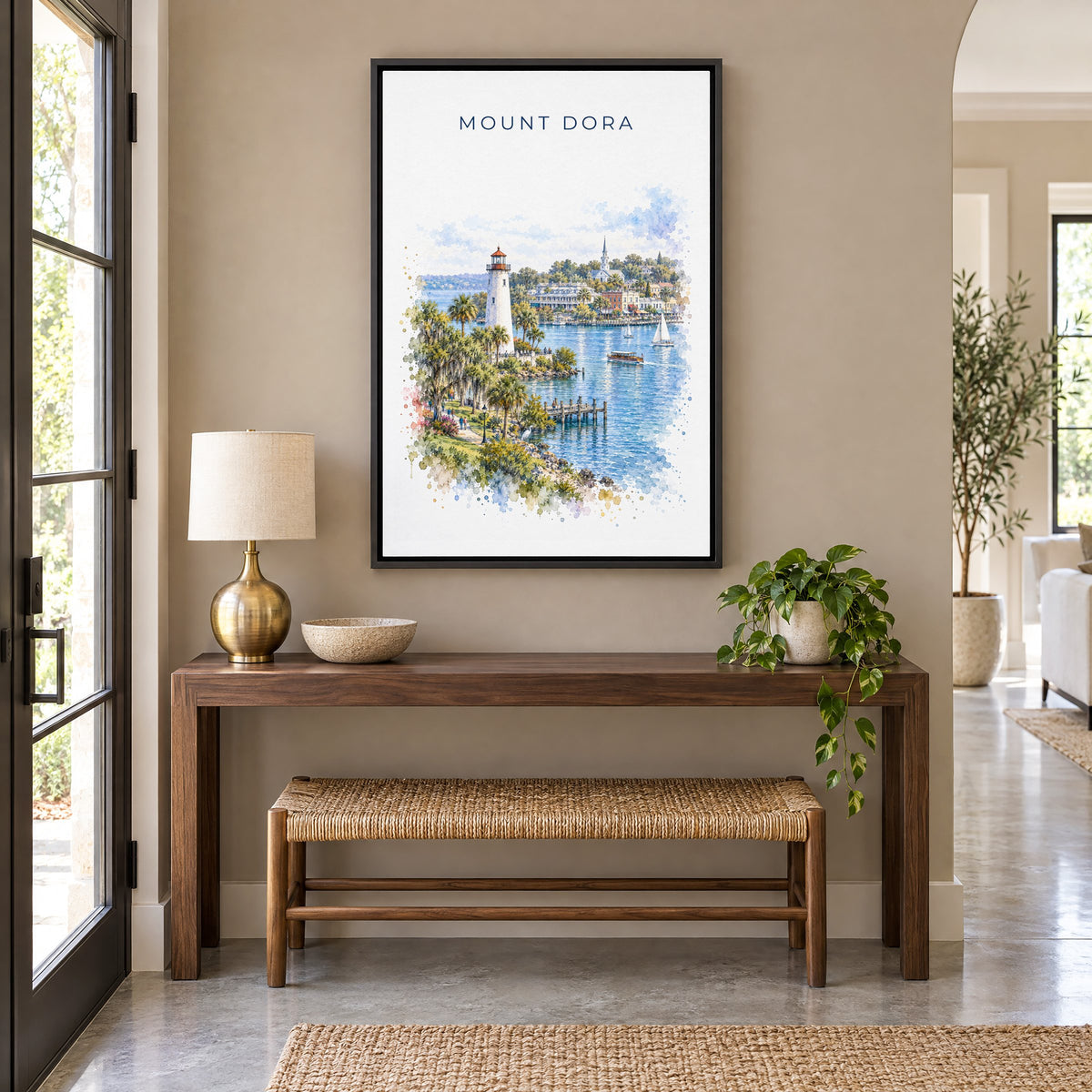 Mount Dora, Florida watercolor print as a black floater canvas above a walnut console and woven bench in an entryway