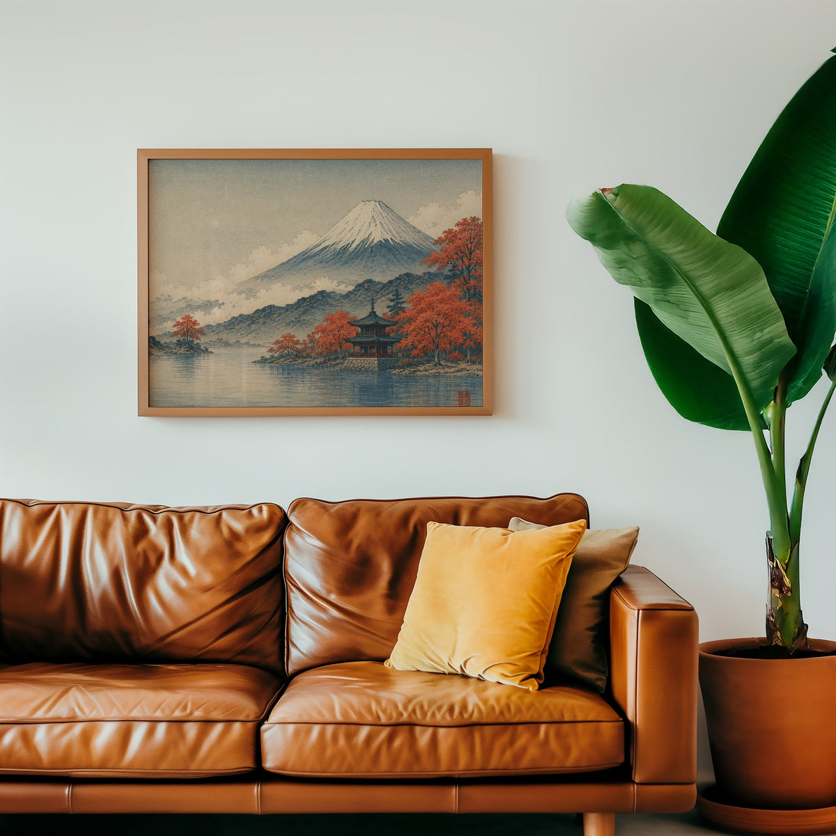 Mount Fuji autumn lake and pagoda print in a warm oak frame above a cognac leather sofa with a mustard pillow