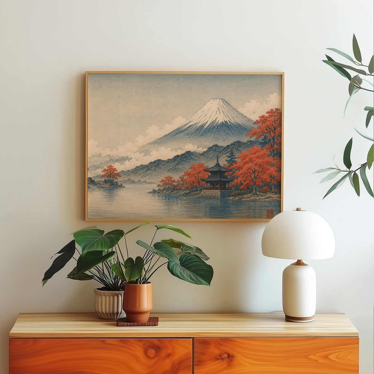 Mount Fuji autumn lake and pagoda print in a light oak frame above a wood sideboard with a white dome lamp