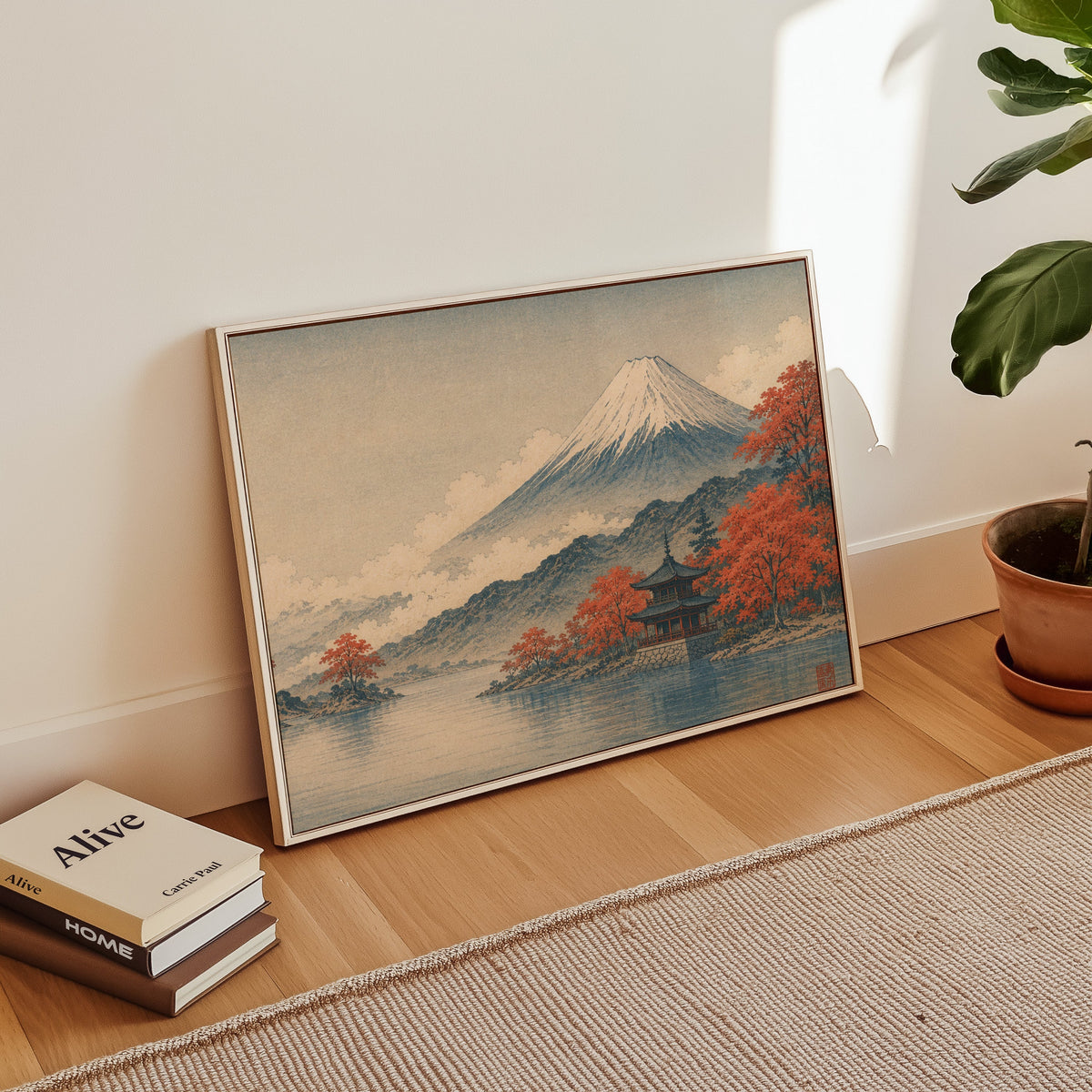 Mount Fuji autumn lake and pagoda print in a white floater frame leaning on a wood floor beside stacked books