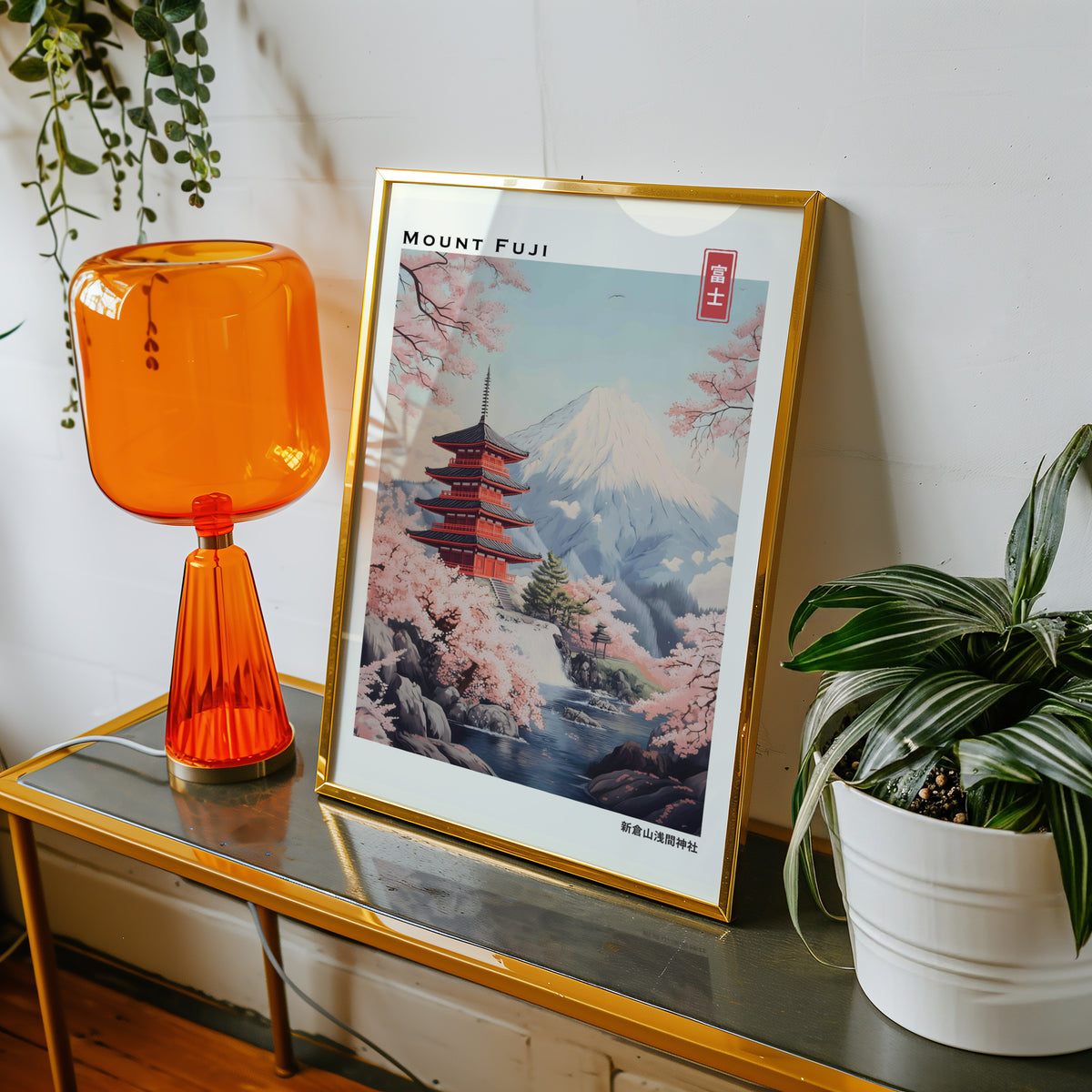 Pastel Chureito Pagoda and Fuji print shown in a gold frame on a console beside an orange glass lamp