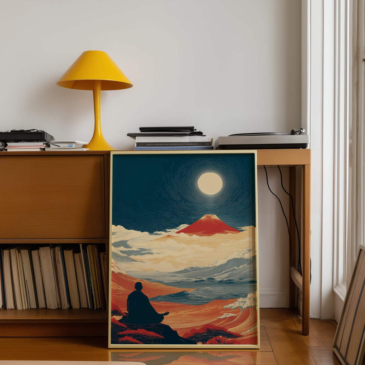 Meditating monk and red Fuji print shown in a gold frame below a teak desk with a yellow lamp