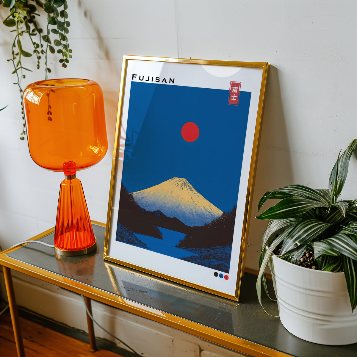 Minimal golden Mount Fuji print shown in a gold frame on a console beside an orange glass lamp