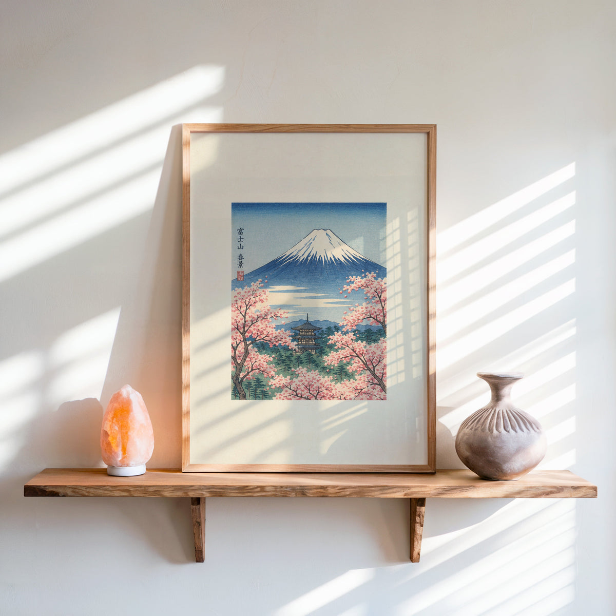 Mount Fuji with pagoda in spring print in an oak frame on a live-edge wall shelf with a salt lamp and clay vase