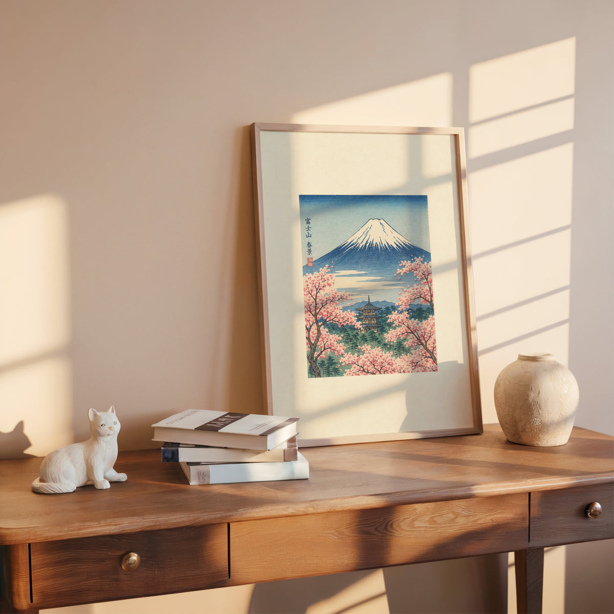 Mount Fuji with pagoda in spring print shown in a rose gold frame leaning on a wooden writing desk with books