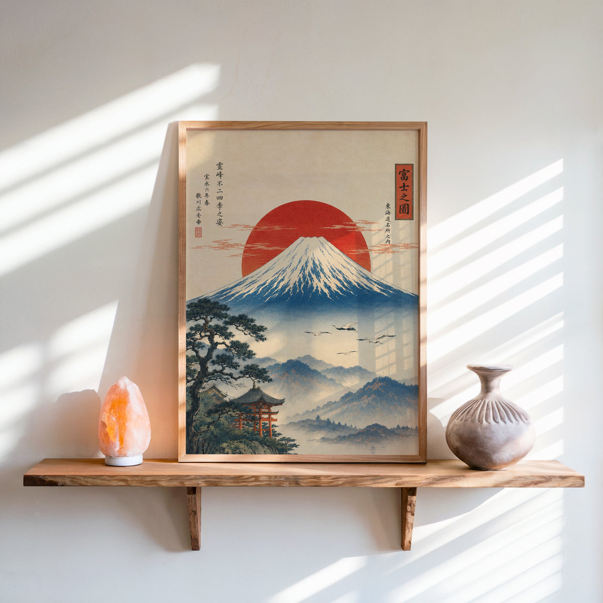 Mount Fuji with red sun and flying cranes print in an oak frame on a live-edge wall shelf with a salt lamp and clay vase