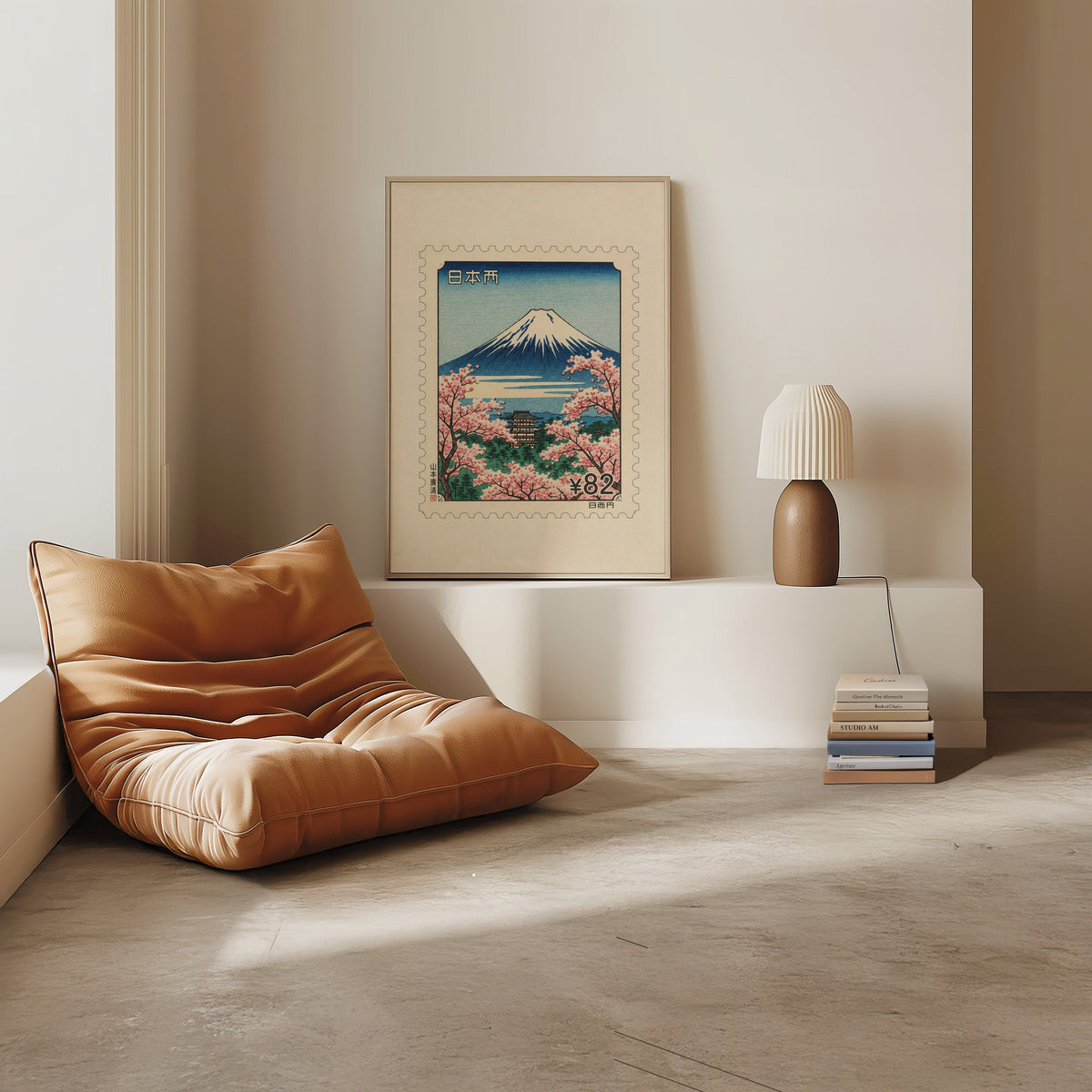 Mount Fuji sakura postage stamp print in a light oak frame on a white ledge by a tan leather floor chair