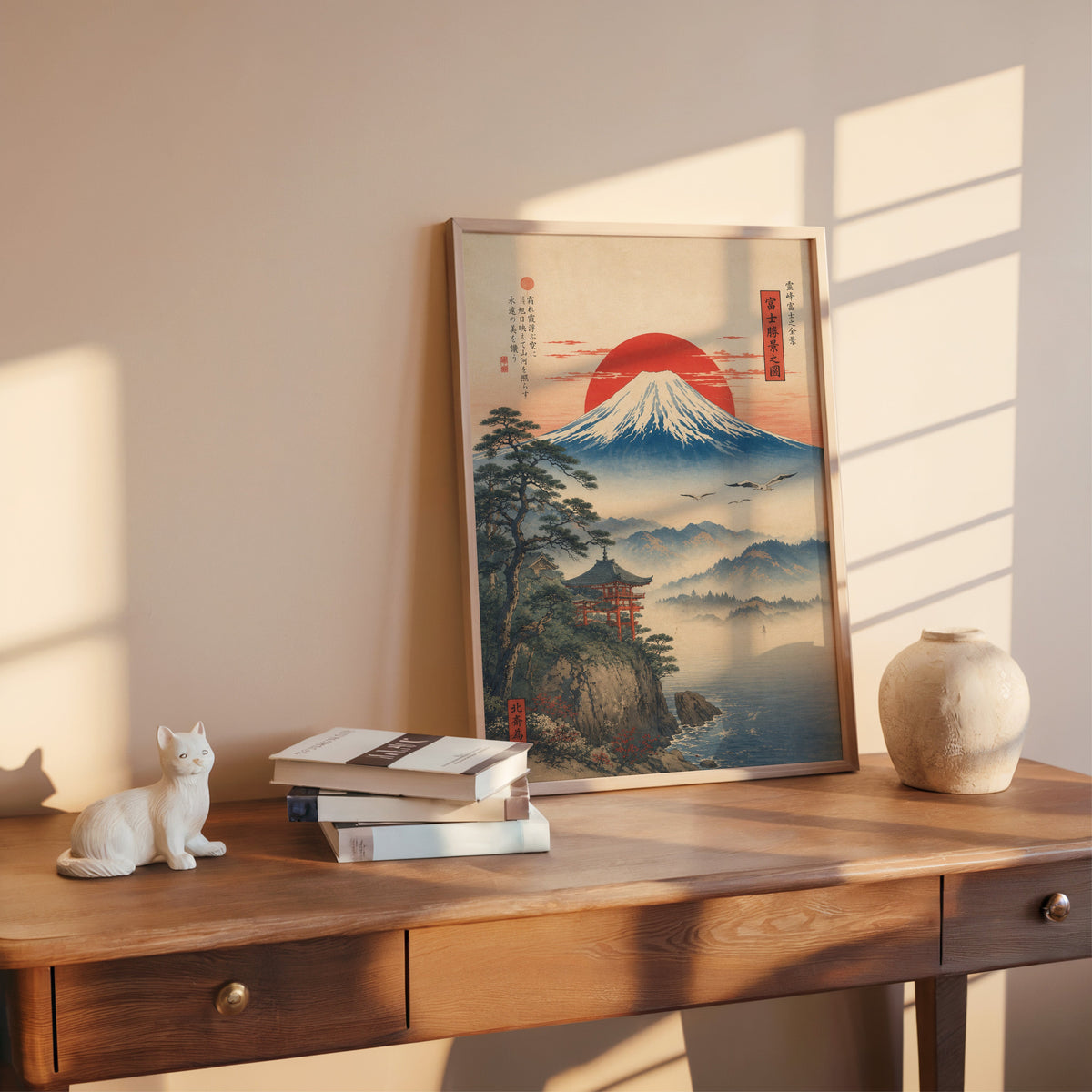 Mount Fuji sunrise with cliff shrine print shown in a rose gold frame leaning on a wooden writing desk with books