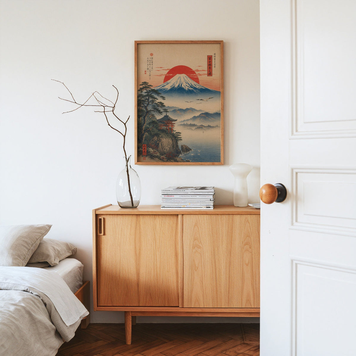 Mount Fuji sunrise with cliff shrine print in an oak frame above an oak sideboard in a bedroom with linen bedding